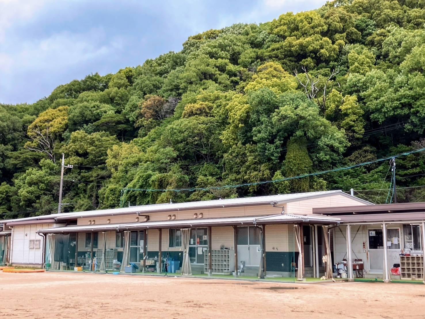 二福のびのびクラブの平屋の建物。背後に緑の濃い山